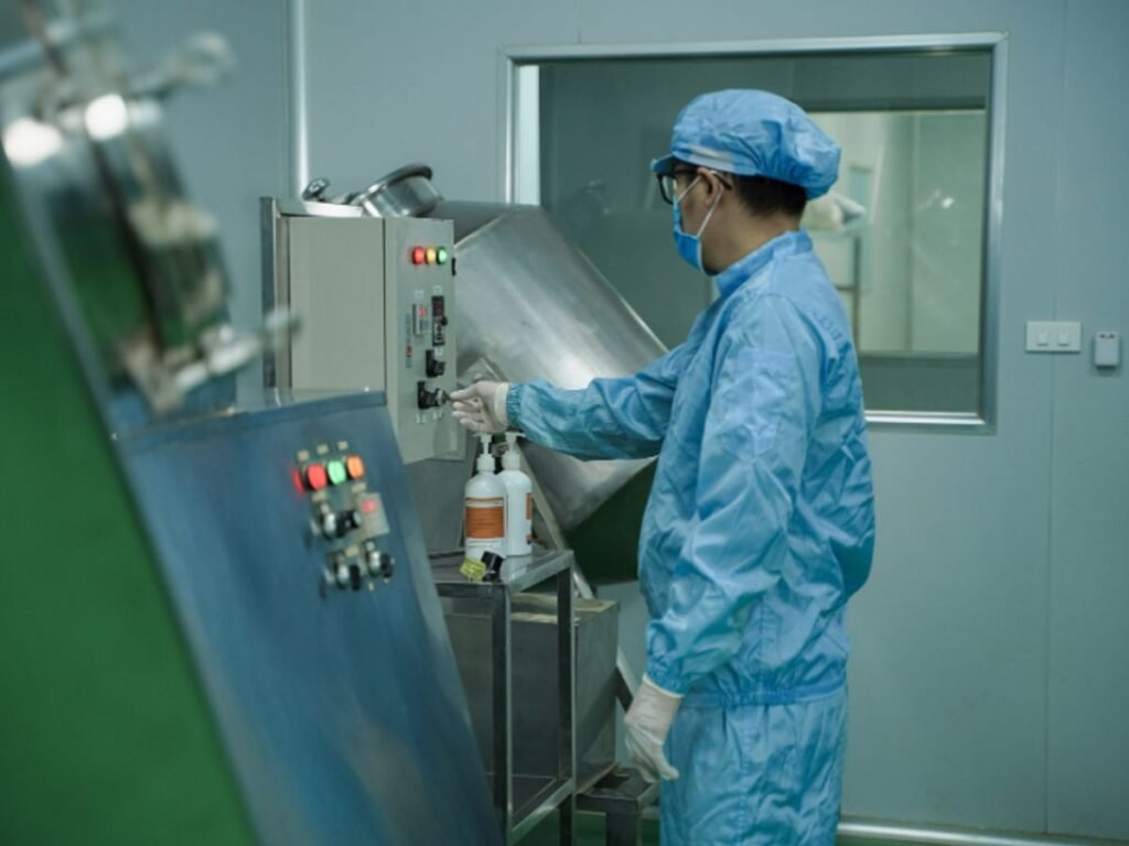A person in protective gear operates machinery in a lab.