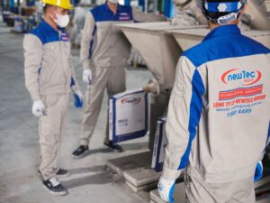 Workers in protective gear handling materials in a warehouse.