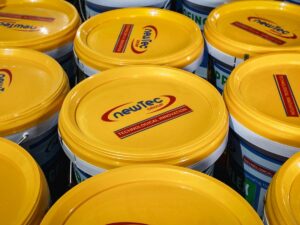 Yellow paint buckets with labels stacked closely together.