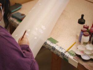 Person painting details on a long, white, textured surface.