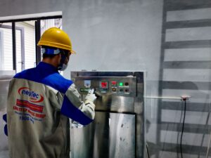 Person operating machinery in a factory setting, wearing safety gear.
